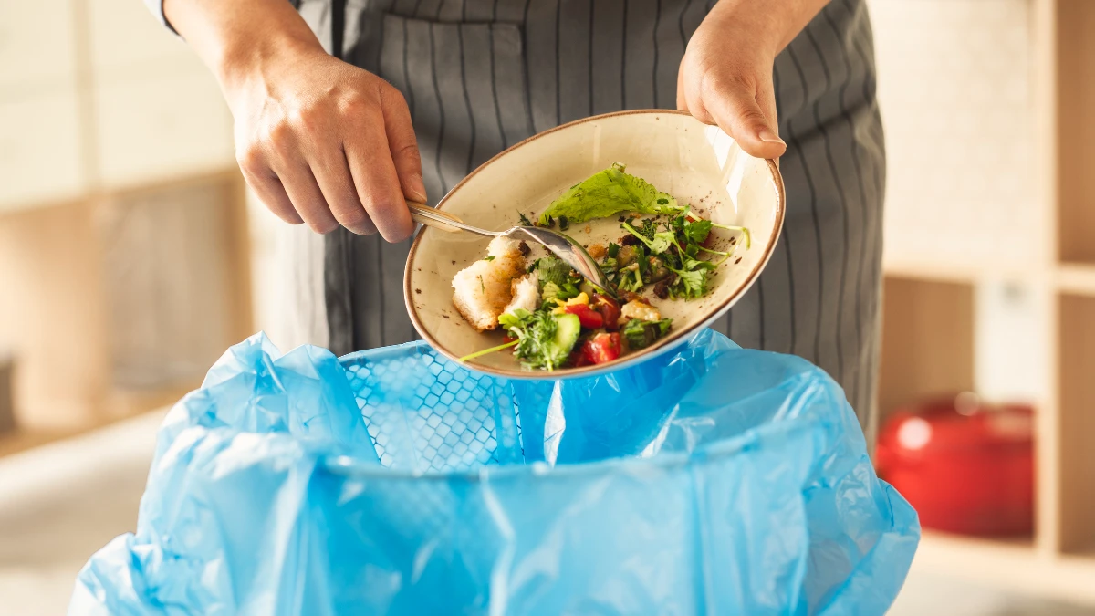 Waitress scraping leftover food from plate into bin