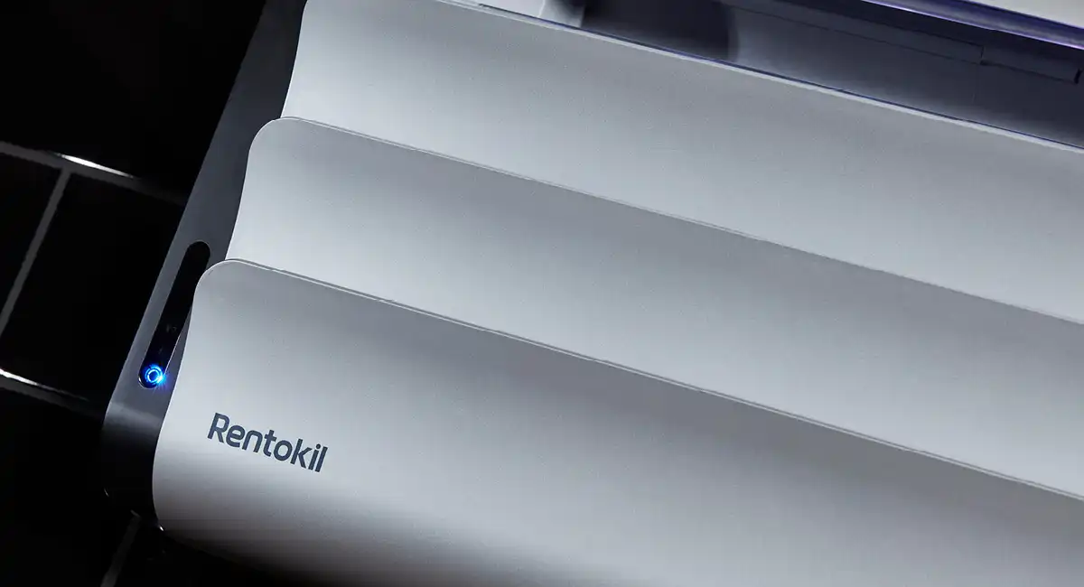 Close-up of a sleek white Rentokil insect light trap with an illuminated blue power indicator LED.