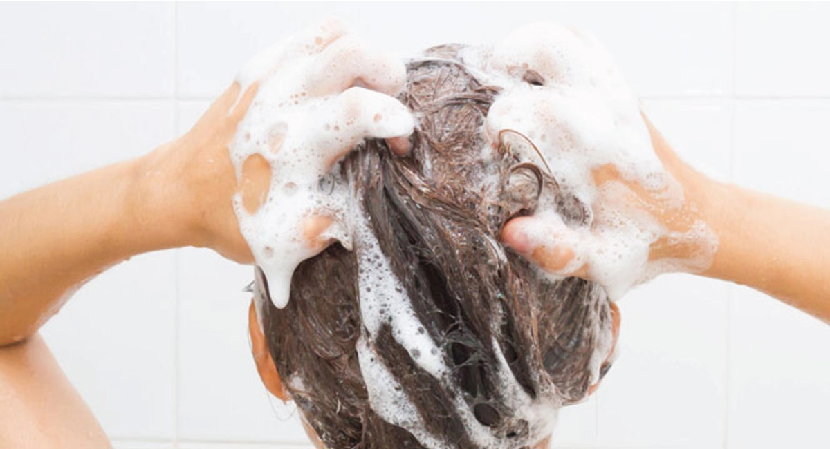 Woman washing hair in the shower with shampoo