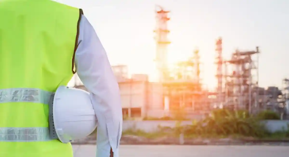 man standing with white safety helmet near to oil refinery