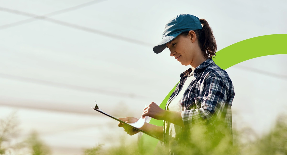 a woman in an baseball cap looks at a clipboard outdoors